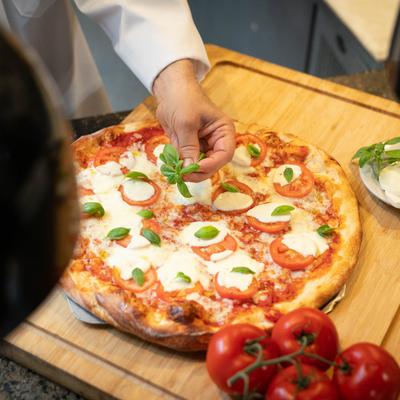 Chef's hands preparing a pizza.