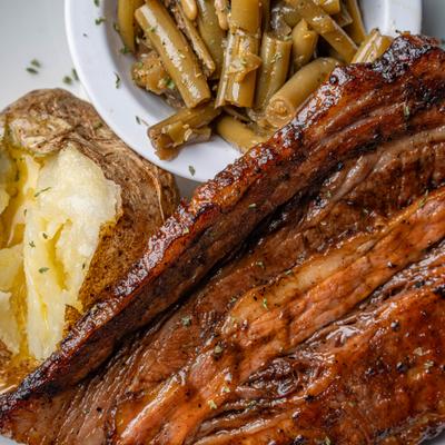 Beef brisket served with green beans and a baked potato.