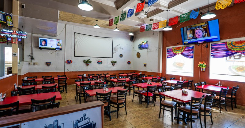 Mexican restaurant interior featuring red tables and colorful festive banners