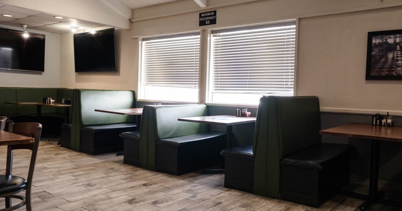 Interior, dining area, seating booths with wooden top tables, tile flooring, TVs on the walls