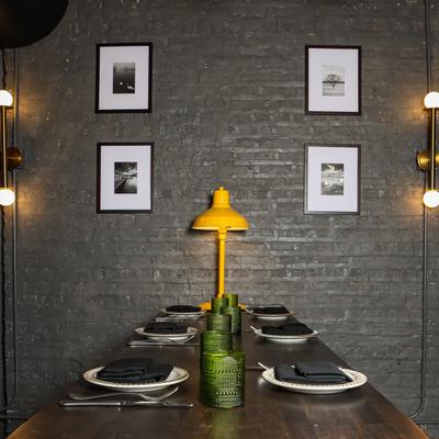 Table setting with plates, napkins and yellow lamp centerpiece, against brick wall with framed art.