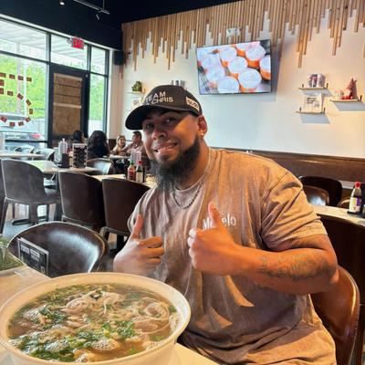 Customer posing with a bowl of soup holding two thumbs up.