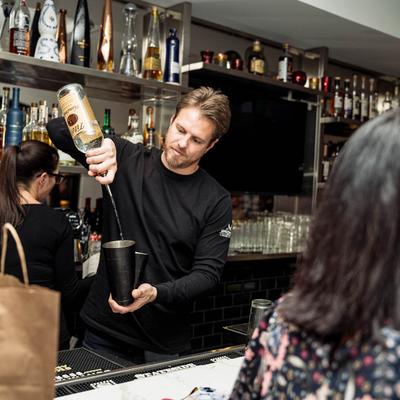 A person preparing a drink to guests.