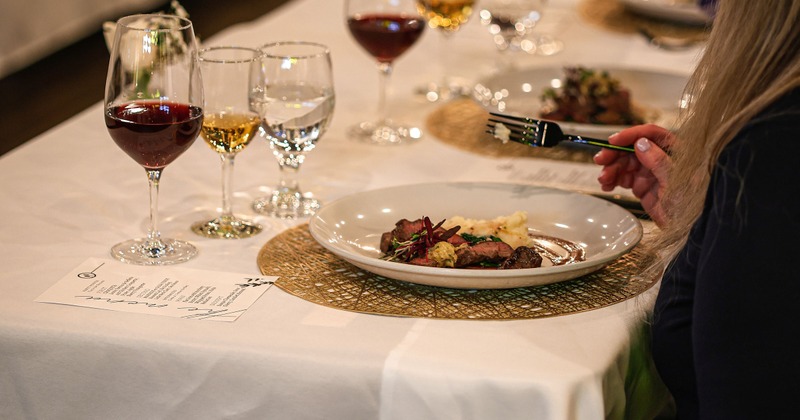 Elegant dining setup with a person eating and glasses of red and white wine