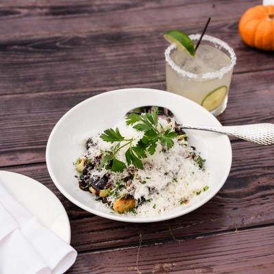 Charred Brussel Sprouts topped with grated cheese, served beside a cocktail.