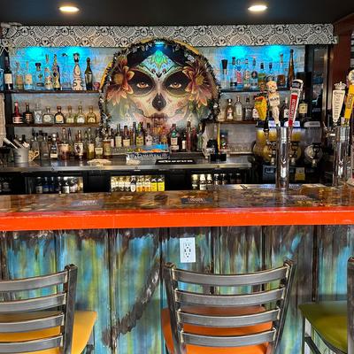 Interior, counter, chairs, bottles of drinks stacked on shelves, beer dispensaries