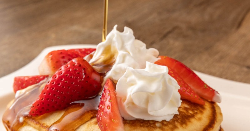 Pancakes, with strawberries, whipped cream, and maple syrup