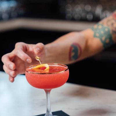 Bartender garnishing a red cocktail
