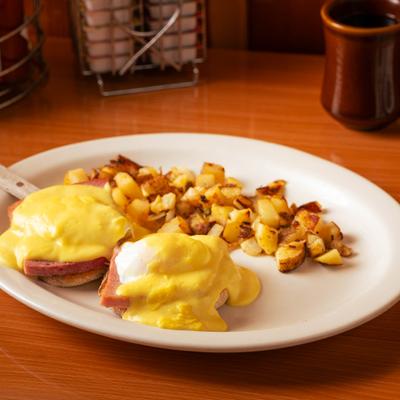 Eggs Benedict served with a side of home-style potatoes.