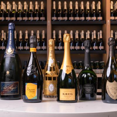 Assorted champagne bottles displayed in front of full shelves.