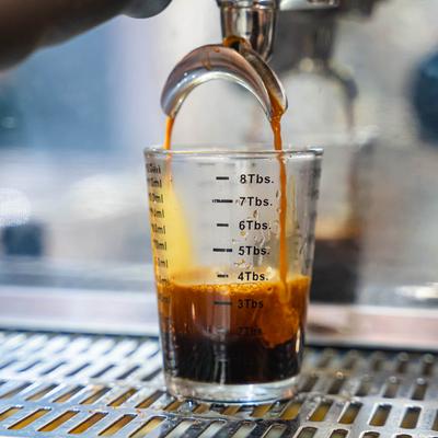 Pouring espresso in a measuring cup.
