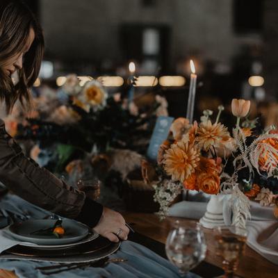 A person sets up a table with flowers and candles to create a beautiful ambiance.