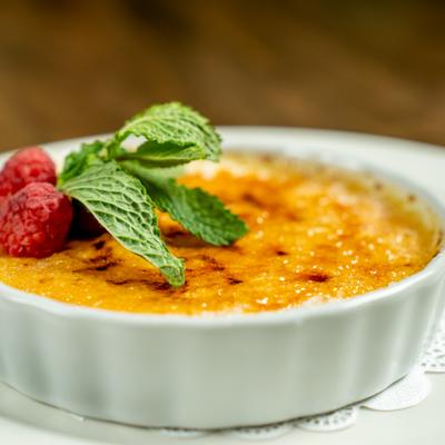 Creme Brulee garnished with fresh raspberries and mint leaves.