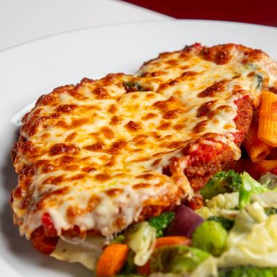 Chicken Parmesan with steamed vegetables and penne in tomato sauce.