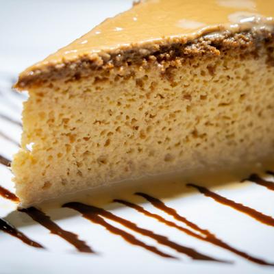 Flan slice on a white plate with chocolate sauce drizzle, close up.