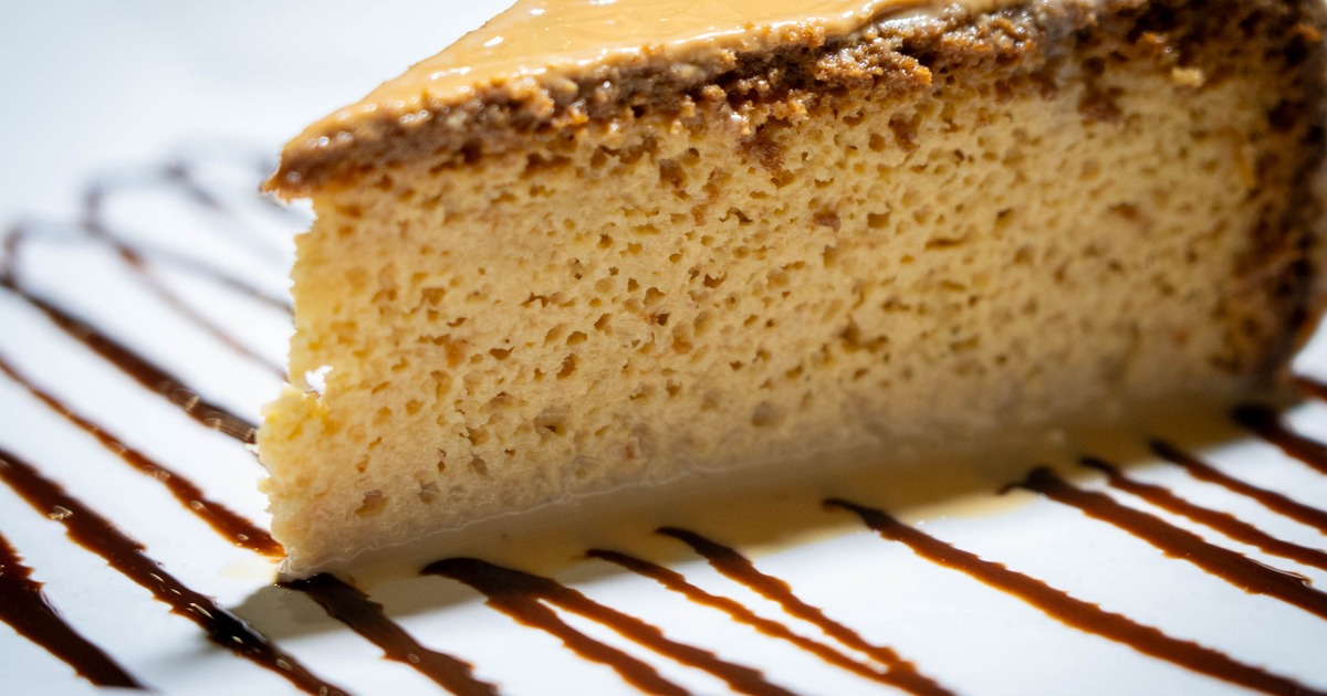 A slice of flan on a chocolate drizzled plate