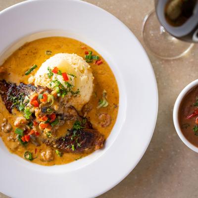 Chicken fillet in tomato sauce, served over rice, with gumbo and red wine on the side