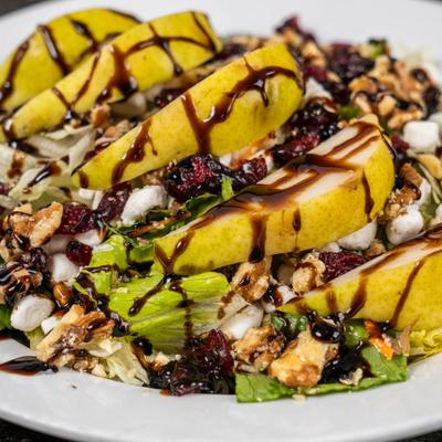 Pear salad with greens, walnuts, dried cranberries, cheese, and balsamic drizzle.