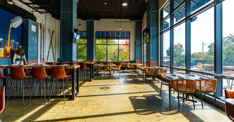 Interior, large windows, wooden tables, and orange-brown chairs