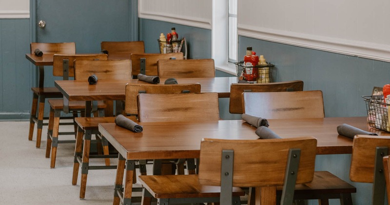 Casual dining area with wooden tables and chairs, TVs on the wall