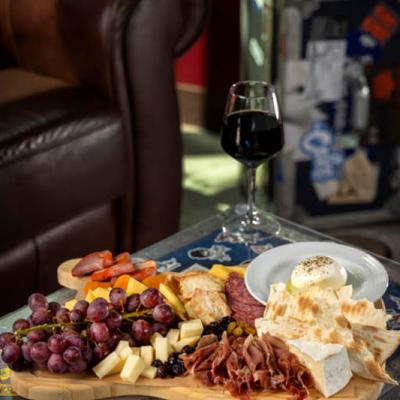 Charcuterie and cheese board with red wine on a table.