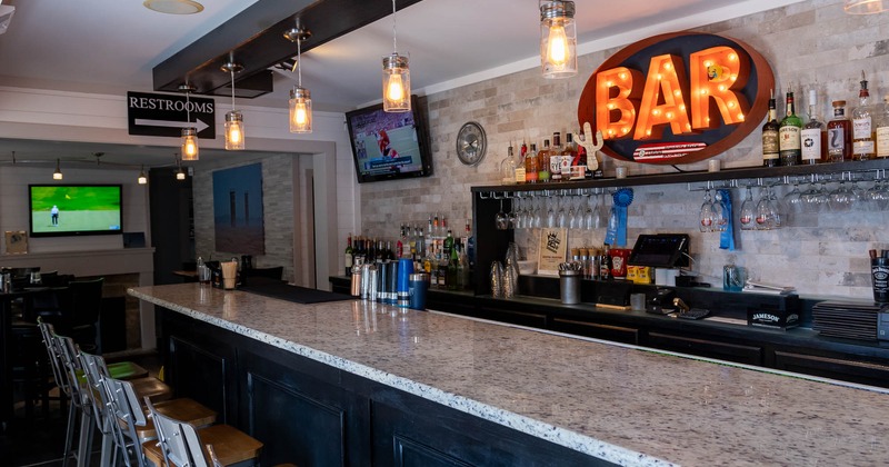 Bar, chairs, light sign on the wall behind