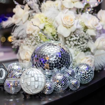 Mirrored ornaments arranged before a white floral centerpiece.