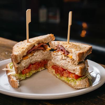 Turkey club sandwich with bacon, lettuce, tomatoes, and cheddar cheese.
