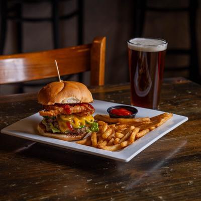 Cowboy burger served with fries, ketchup, and a pint of beer.