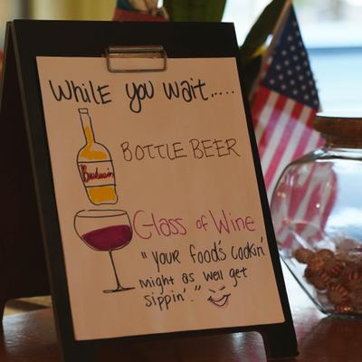 Sign that suggest customers pass the time with a drink while their food is being prepared.