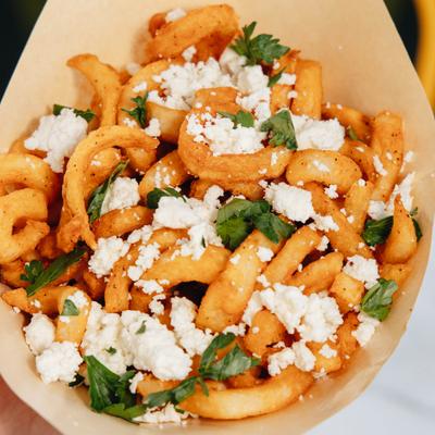 Curly Feta Fries featuring crumbled cheese and fresh herbs.