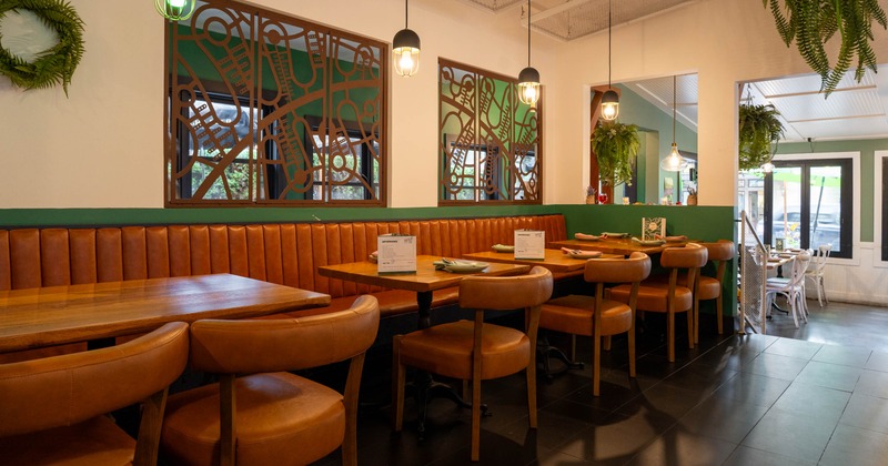 Modern restaurant interior with brown leather seating, pendant lighting, and decorative wooden wall art