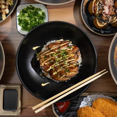 Pork belly bowl with Japanese octopus balls and mashed potato croquettes on a table.