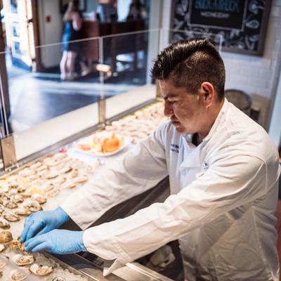 Kitchen staff member arranging oysters on an oyster display.