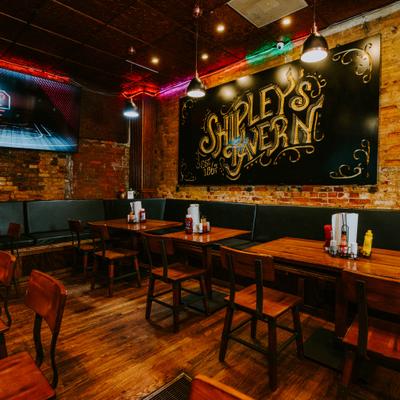 Interior with table seating, overhead lighting and a large chalk sign on the exposed brick wall.