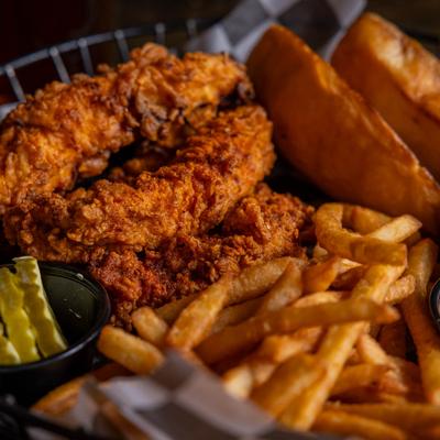 Fried chicken tenders with fries and pickles.