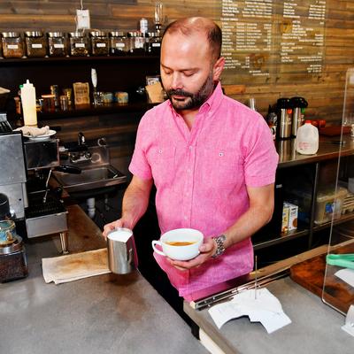 A barista preparing coffee with milk.