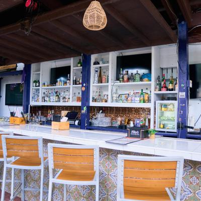 Open air bar with wooden stools and hanging lights.