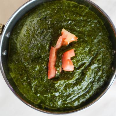 Palak Paneer garnished with diced tomato, overhead view.