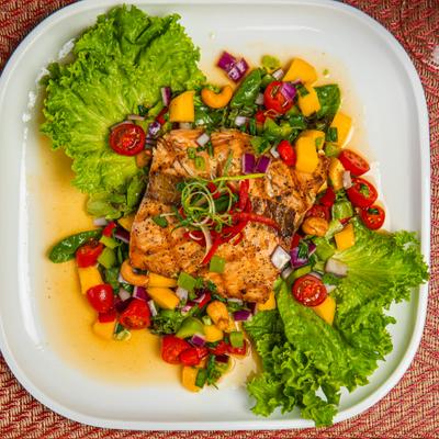 Grilled salmon served over the mango salad, overhead view.