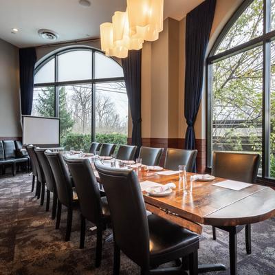 Dining room with a set table, modern lighting, and large arched windows.