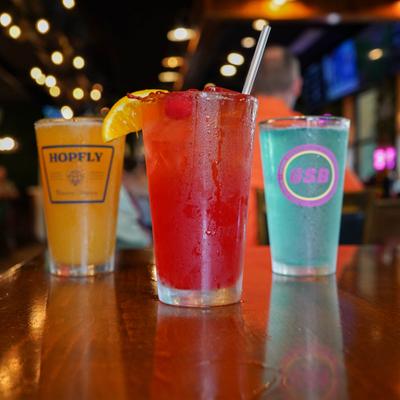 Three colorful drinks lined across a wooden table.