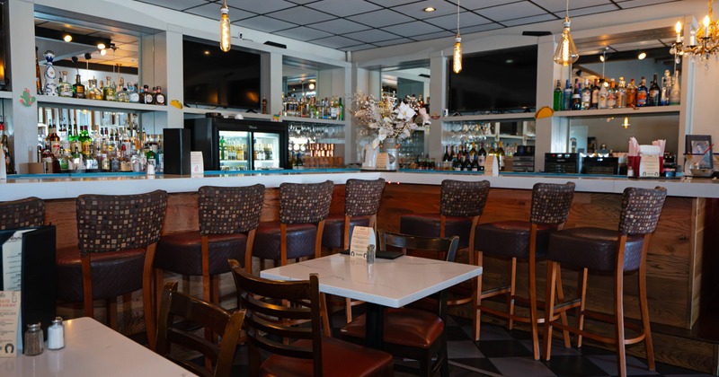 Interior, bar with high-backed stools, a well-stocked counter, and a small dining area