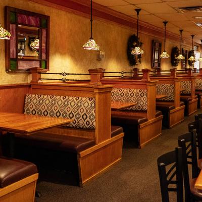Restaurant interior with wooden booths under stained glass pendant lights.