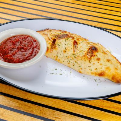 Calzone served on the plate with a side of marinara sauce.