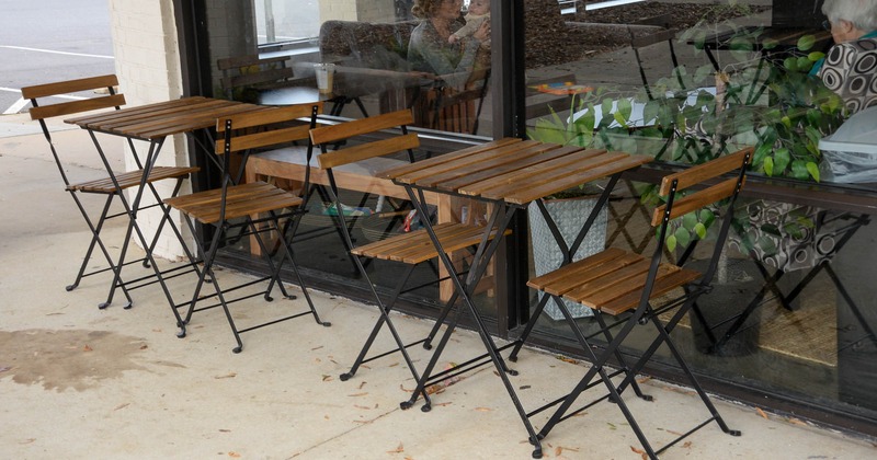 Two tables with chairs outside the coffee bar