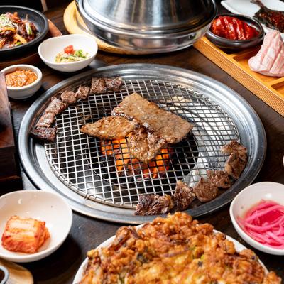 A grill in the middle of the table and served food around it.