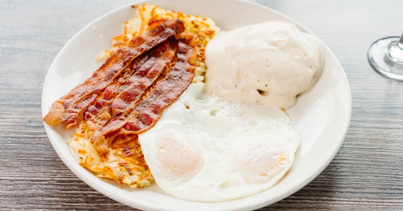 Country Breakfast with fried egg, hash browns, bacon and gravy-topped biscuit