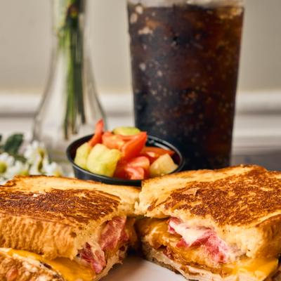 Turkey Melt Sandwich served with a small salad and a glass of iced soda.