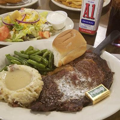 Grilled steak served with mashed potatoes, green beans and a bread roll.